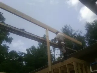 Carpenter setting a ridge beam over a new addition frame — Ice Dam Removal by Roofing Brothers in Mcintosh