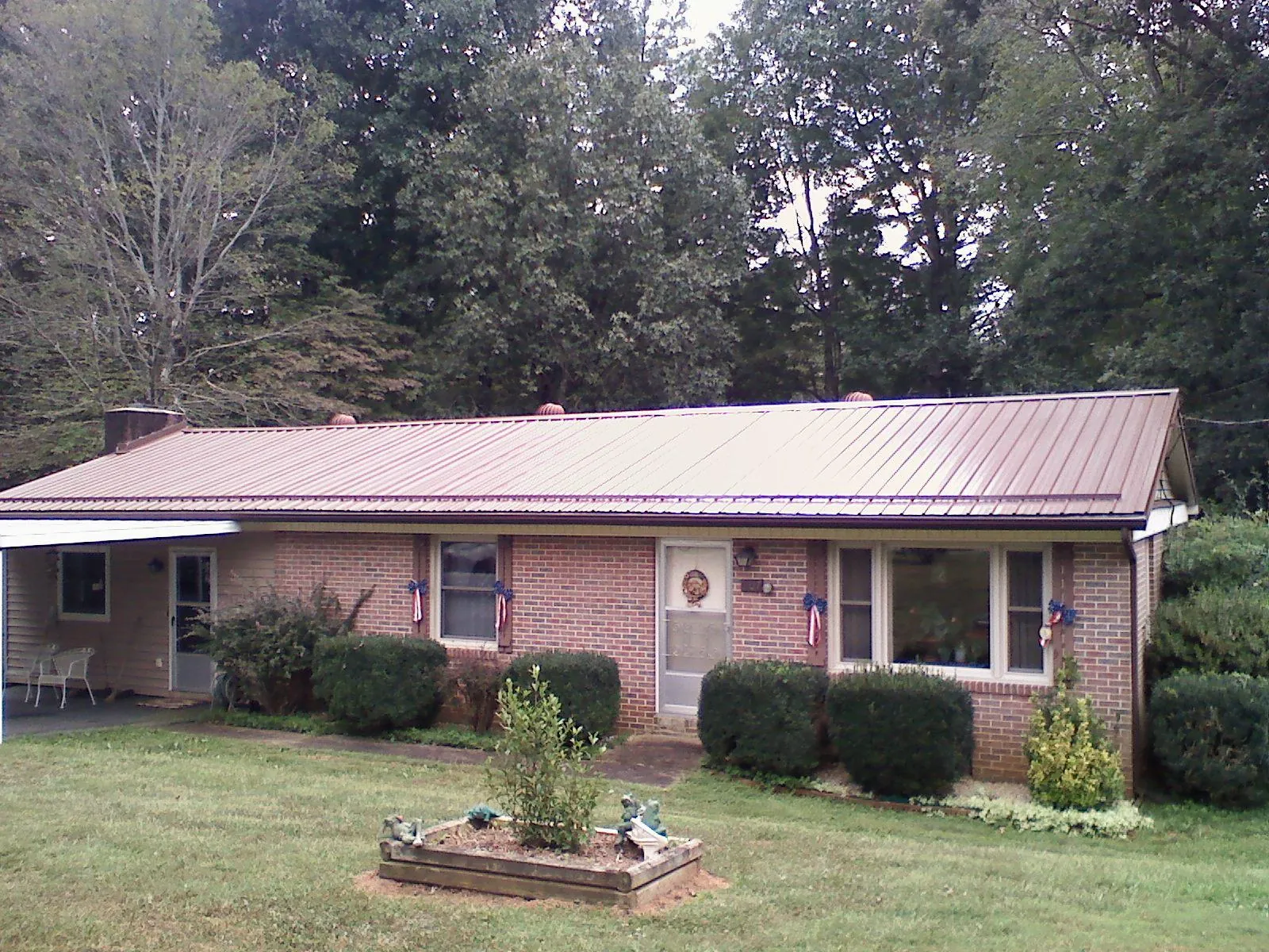Bronze metal roof on a brick ranch home with a carport in Mcintosh