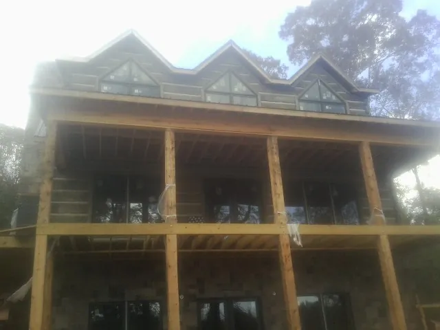 Dormers and porch framing on a large log home under construction — Roof Coating work by our crew in Mcintosh