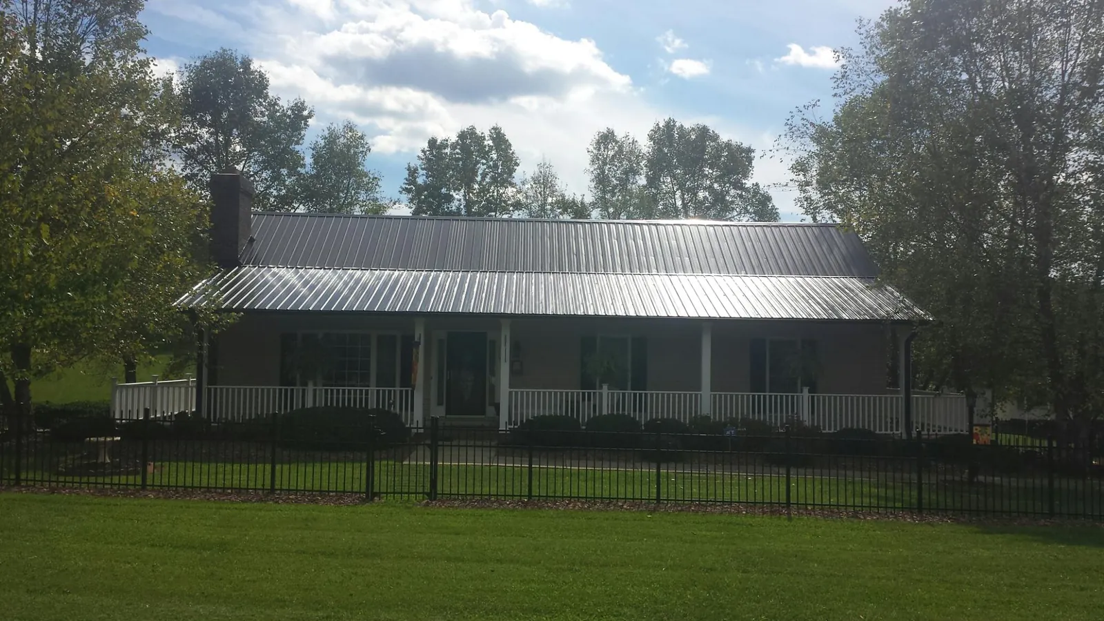 Gray metal roof on a brick ranch with a full width front porch — Gutter Guard Installation work by our crew in Mcintosh