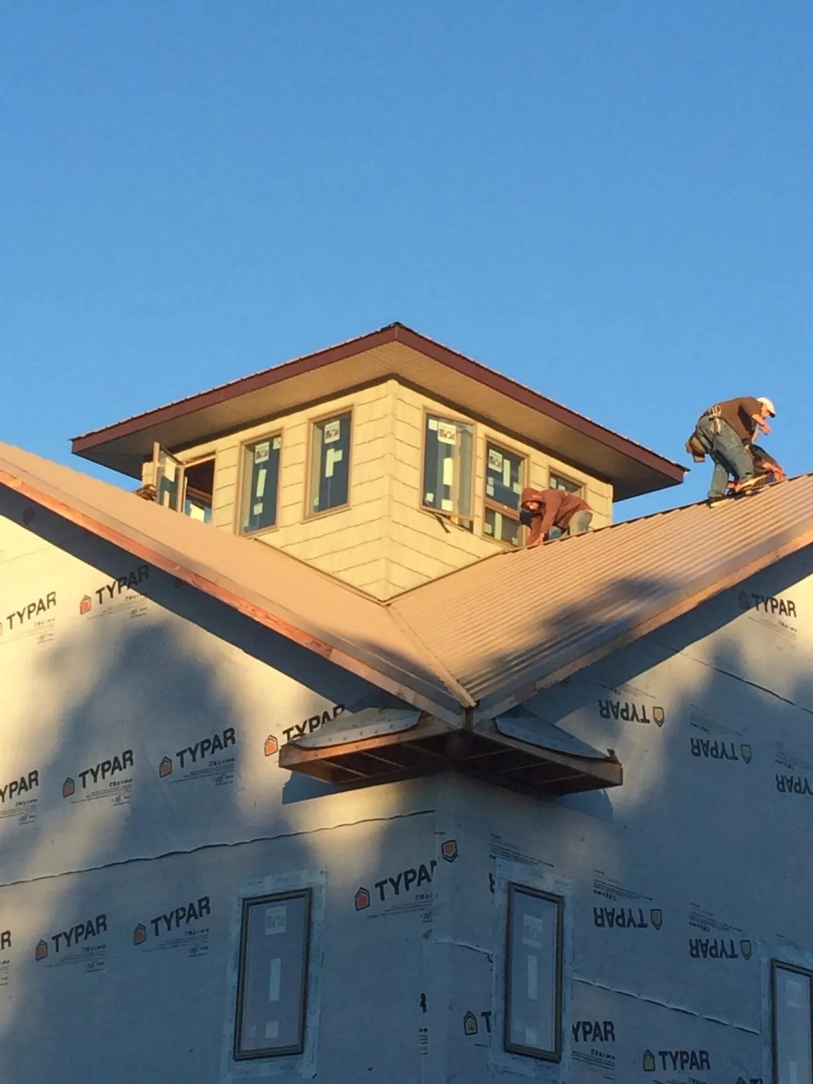 Roofers working around a rooftop cupola on a new metal roof at sunset — Roof Waterproofing in Mcintosh by Roofing Brothers